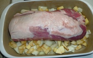 Pork loin in roasting pan on apples and onions