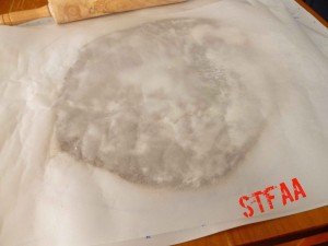 Dough being rolled between two pieces of parchment 