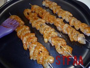 Using a basting brush to coat shrimp with Cajun Seasoning oil mixture