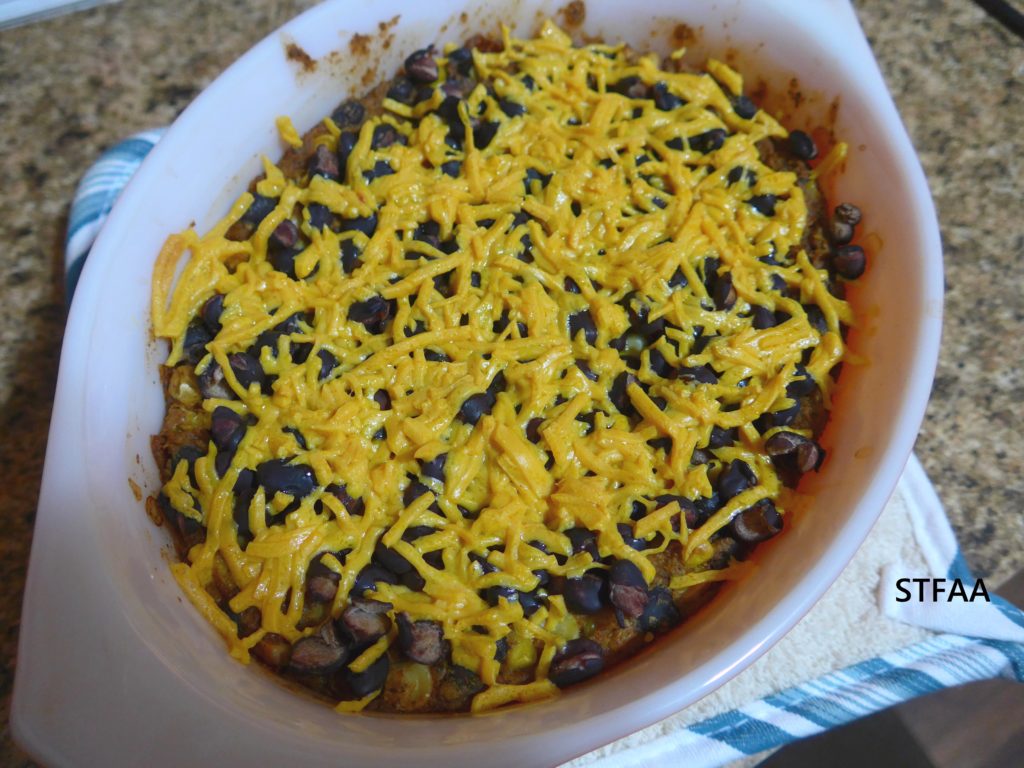 Casserole dish holding a cheese-topped meal with black beans