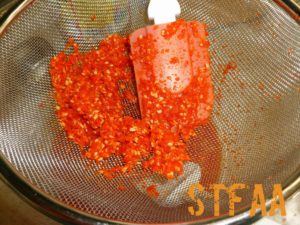 Pushing pulp through strainer to strain out skin and seeds