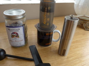 Mountain Thunder coffee, Aeropress set up on a Star Trek mug, JavaPresse grinder, stirring paddle and scoop that came with the Aeropress.